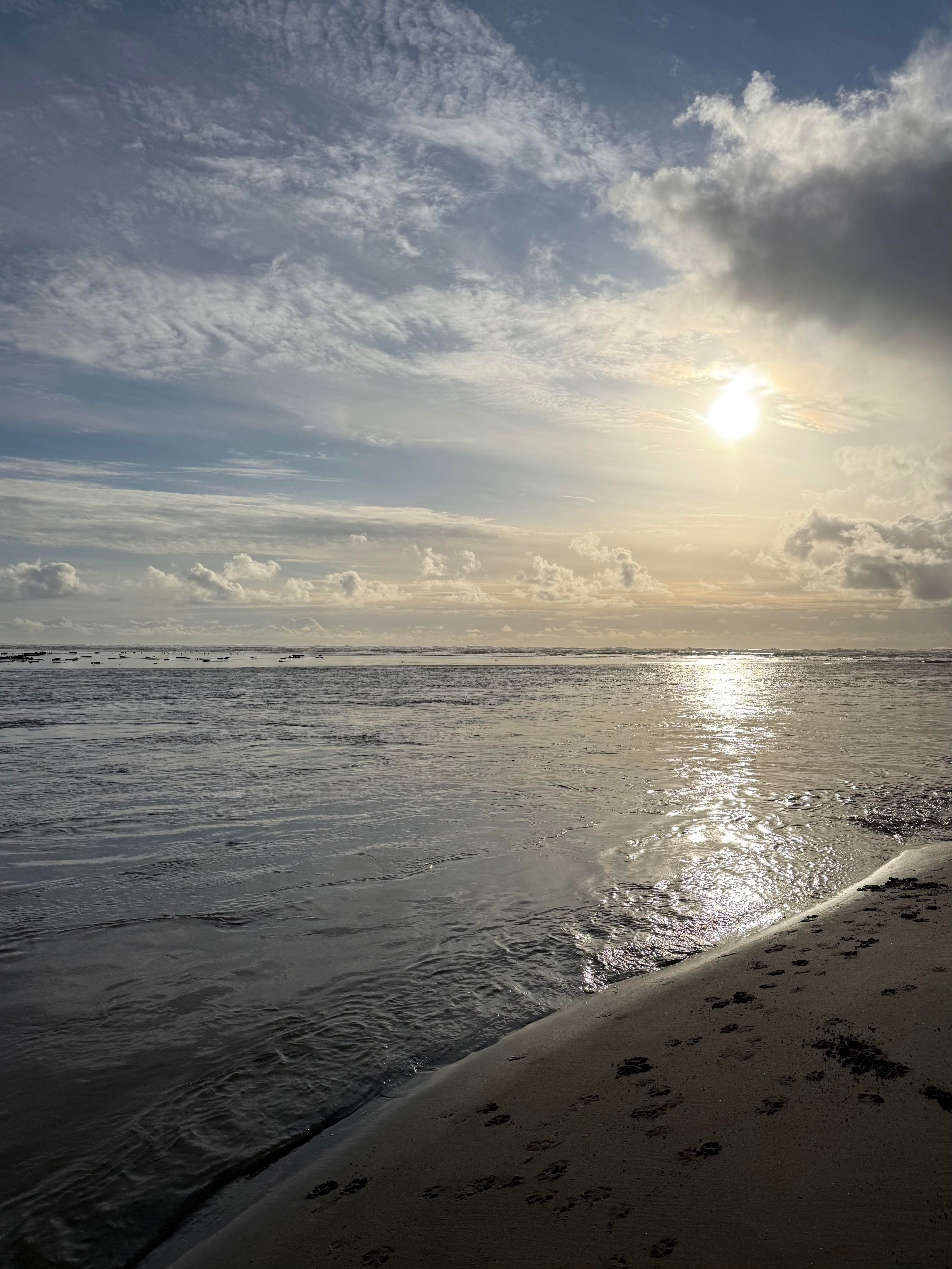 Sunset over a beach with clouds and water reflection