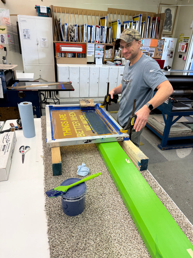 a man screen printing text onto a large, long, neon green object